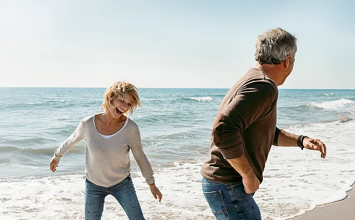 Paar mittleren Alters, das am Strand spielt und Spaß hat.